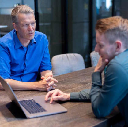 Zwei Männer in einer professionellen Besprechung vor einem Laptop, repräsentiert Beratung und Zusammenarbeit im Online-Marketing für Anwälte